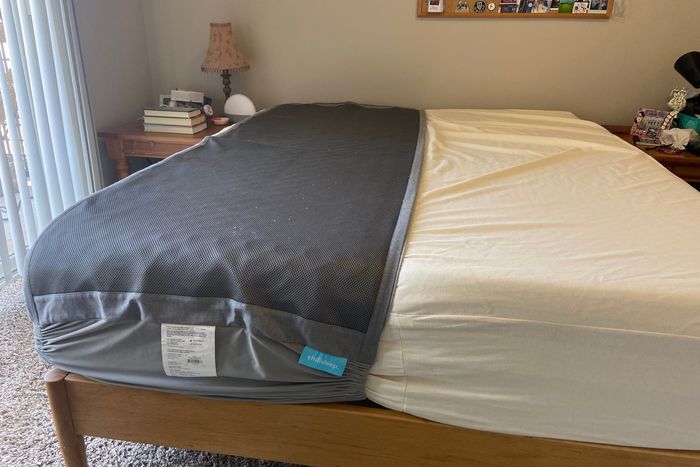 An unmade bed, with the Chilipad shown on one half of the bed.