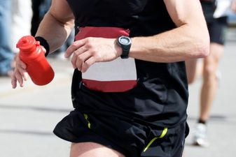 Runner wears a GPS watch and holds bottle of water