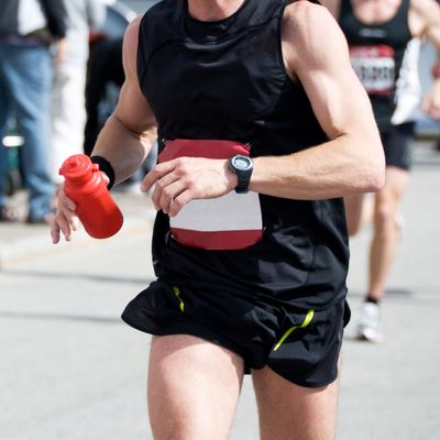 Runner wears a GPS watch and holds bottle of water