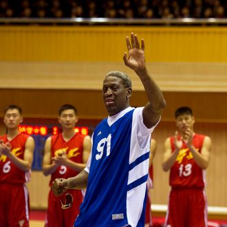 Dennis Rodman waves to North Korean leader Kim Jong Un, seated above in the stands, after singing Happy Birthday to Kim before an exhibition basketball game with U.S. and North Korean players at an indoor stadium in Pyongyang, North Korea on Wednesday, Jan. 8, 2014. (AP Photo/Kim Kwang Hyon)