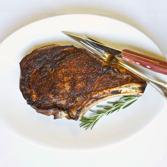 12 Jul 2010 --- Rib Eye Steak on a White Plate; Rosemary Sprig; Knife and Fork.