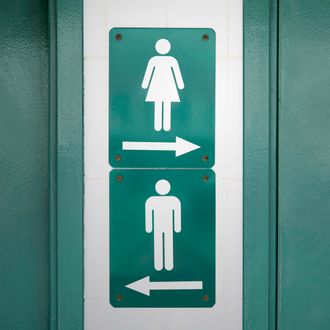 Green sign with male and female symbols directed to go in opposite directions