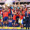 Donald Trump stays on stage as Spain's football team celebrates their World Cup victory.