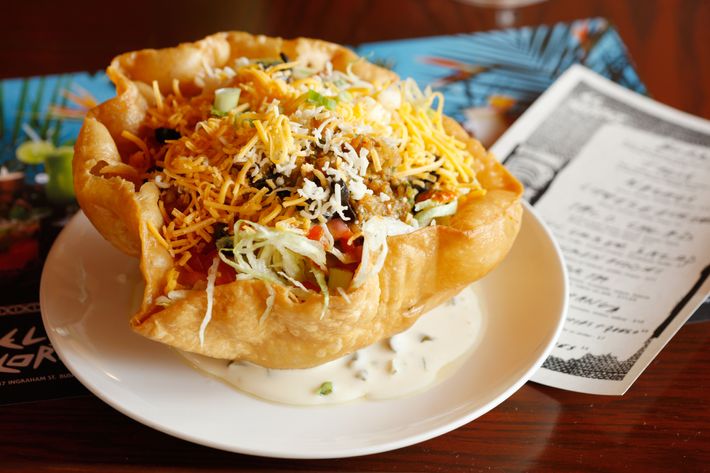 Tanner's taco salad is made with ground beef, black olives, lettuce, cheddar, sour cream, tomato, and beans.