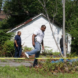 East Cleveland police search near where three bodies were recently found Sunday, July 21, 2013, in East Cleveland, Ohio. The bodies, believed to be female, were found about 100 to 200 yards (90 to 180 meters) apart, and a 35-year-old man was arrested and is a suspect in all three deaths, though he has not yet been charged, East Cleveland Mayor Gary Norton said Saturday. (AP Photo/Tony Dejak)