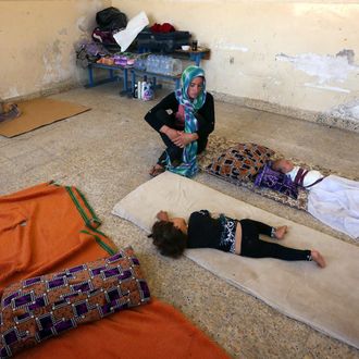 An Iraqi Yazidi mother who fled the violence in the northern Iraqi town of Sinjar, sits with her children at a school where they are taking shelter in the Kurdish city of Dohuk in Iraq's autonomous Kurdistan region, on August 5, 2014. Islamic State (IS) Sunni jihadists ousted the Peshmerga troops of Iraq's Kurdish government from the northern Iraqi town of Sinjar, forcing thousands of people from their homes. The Yazidis, are a small community that follows a 4,000-year-old faith and have been repeatedly targeted by jihadists who call them 