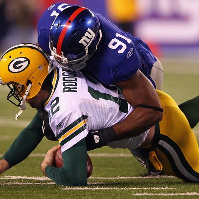 Aaron Rodgers #12 of the Green Bay Packers is sacked by Justin Tuck #91 of the New York Giants in the second quarter at MetLife Stadium on December 4, 2011 in East Rutherford, New Jersey.