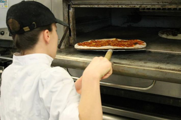 A student puts a pie into the oven.