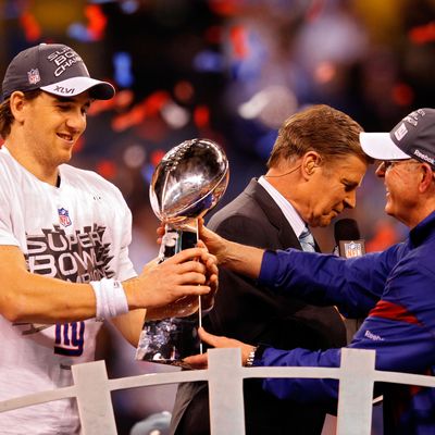 Eli Manning #10 of the New York Giants poses with the Vince Lombardi Trophy and his head coach Tom Coughlin after the Giants defeated the Patriots by a score of 21-17 in Super Bowl XLVI at Lucas Oil Stadium on February 5, 2012 in Indianapolis, Indiana.