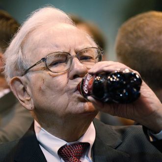 Berkshire Hathaway CEO Warren Buffett drinks a bottle of Coca Cola during at a trade show at the company's annual meeting in Omaha, Nebraska May 3, 2014. 