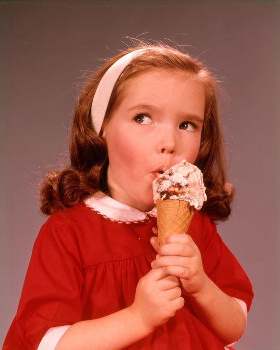 A vintage portrait of a little girl in a red dress licking an ice cream cone.