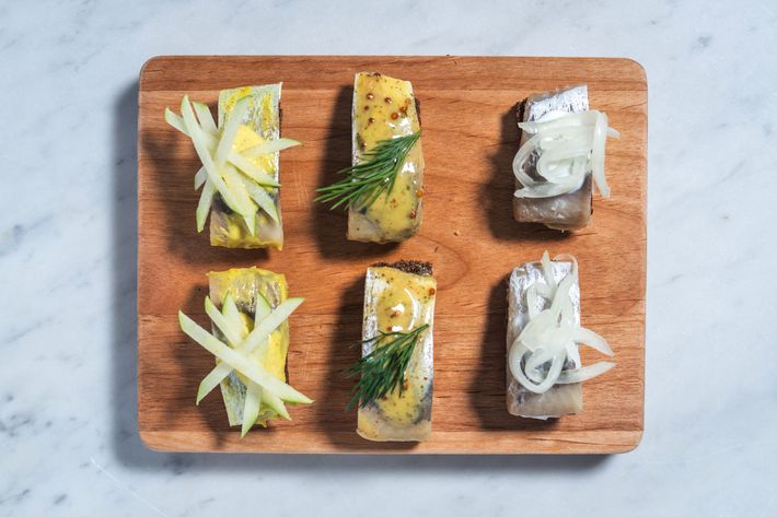 Canapés of pickled herring on pumpernickel bread: mustard and dill herring; curry herring with green apple; and pickled herring with cream sauce and pickled onions.