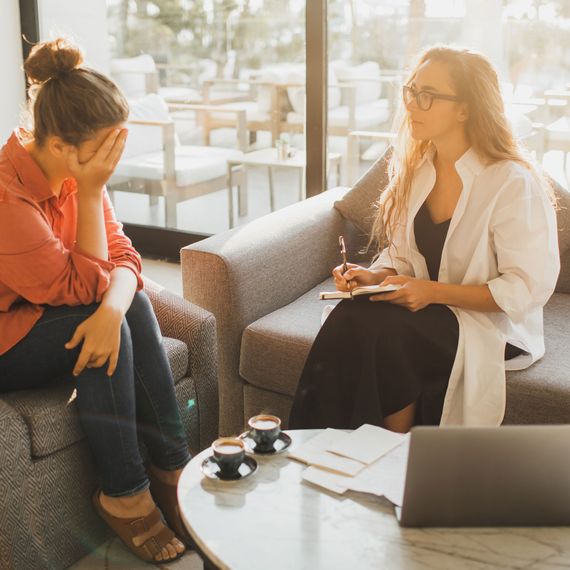Woman psychologist in glasses consulting woman in office clinic interior.