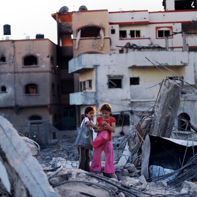 Shahed Abood (R), 7, and her cousin Ali (L), 9, look at some of the belonging they salvaged from their destroyed homes on August 11, 2014 in Jabalia, northern Gaza Strip. The girls and their families sought refuge in a UN school fled their neighborhood when fighting broke out between Israel military and Hamas a little over 4 weeks ago. A fresh 72-hour ceasefire between Israel and Hamas came into effect in Gaza today, paving the way for talks in Egypt aimed at a durable end to a month-long conflict that has wreaked devastating bloodshed. AFP PHOTO/ROBERTO SCHMIDT (Photo credit should read ROBERTO SCHMIDT/AFP/Getty Images)
