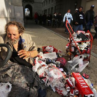 WASHINGTON, DC - JANUARY 21: People walks past a homeless man who did not want to be identified on their way to the National Mall to attend the Inauguration ceremony on January 21, 2013 in Washington, DC. U.S. President Barack Obama, will be ceremonially sworn in for his second term today. (Photo by Mario Tama/Getty Images)