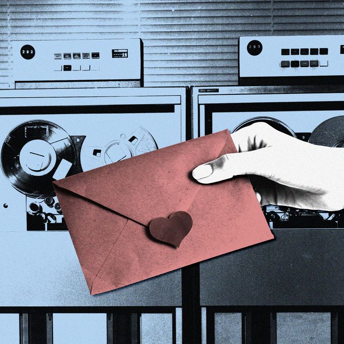 In this photo illustration, a hand holds a pink envelope sealed with a heart sticker in front of a 1960s-era computer.