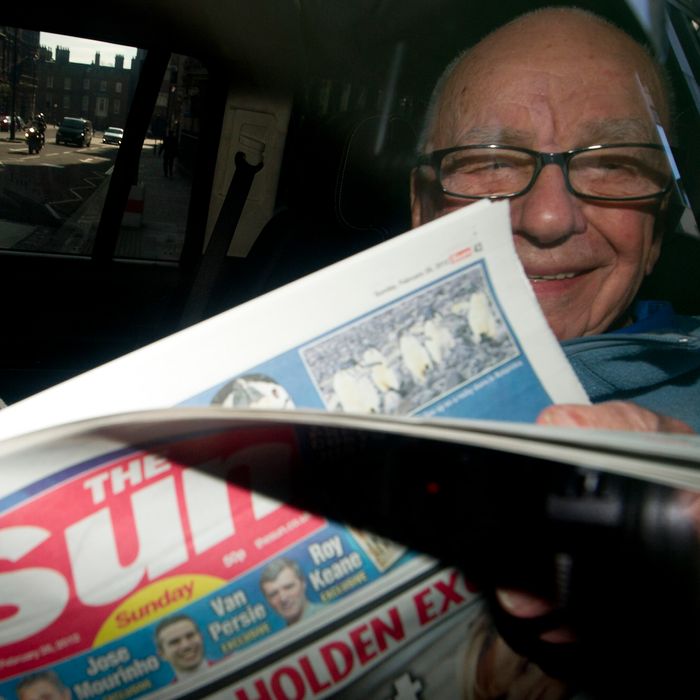 News Corporation Chief Rupert Murdoch holds up a copy of the newly launched 'The Sun on Sunday' newspaper as he leaves his London home on February 26, 2012.