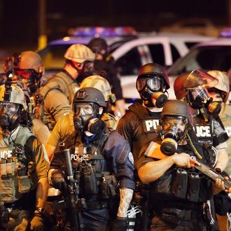 FERGUSON, MO - AUGUST 17: Police advance on demonstrators protesting the killing of teenager Michael Brown on August 17, 2014 in Ferguson, Missouri. Police shot smoke and tear gas into the crowd of several hundred as they advanced near the police command center which has been set up in a shopping mall parking lot. Brown was shot and killed by a Ferguson police officer on August 9. Despite the Brown family's continued call for peaceful demonstrations, violent protests have erupted nearly every night in Ferguson since his death. (Photo by Scott Olson/Getty Images)