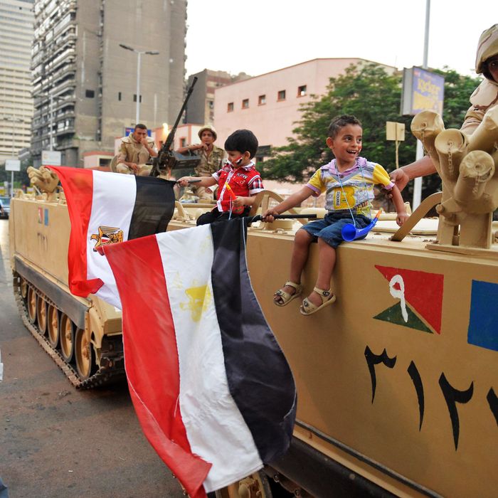 Egyptian children hold national flags as they pose for pictures near army soldiers on an armoured personnel carrier (APC) in a Cairo street on July 3, 2013 after the Egyptian army deployed dozens of armoured vehicles near gathering of Islamist President Mohamed Morsi's supporters. Opposition leader Mohamed ElBaradei and the heads of the Coptic Church and Al-Azhar -- Sunni Islam's highest seat of learning -- will unveil an army roadmap for Egypt's future after President Mohamed Morsi, state television said. 