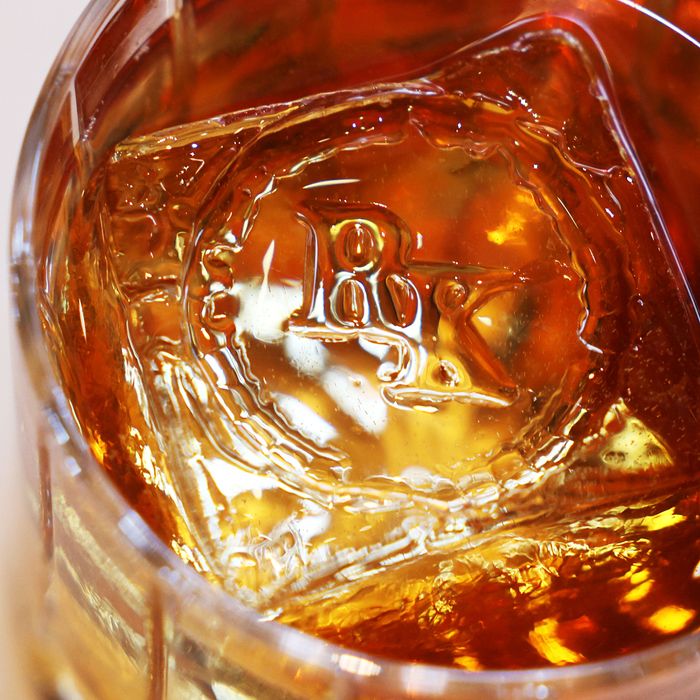A clear amber drink with a giant ice cube monogrammed with RK