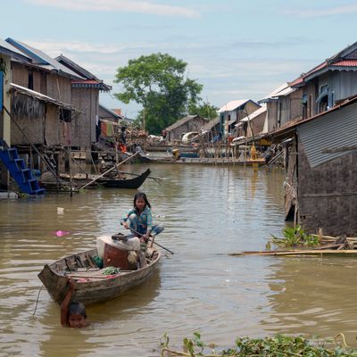 A girl in Kandal province, Cambodia, rows a boat through a flooded village.
