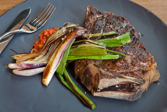 Bone-in aged NY strip: charred spring onions, and romesco.