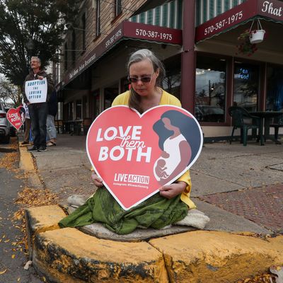 A woman holds an anti-abortion placard as she kneels in