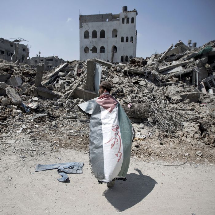 A Palestinian man, wrapped in his national flag, inspects the rubble of destroyed buildings and houses in the Shejaiya residential district of Gaza City, on July 28, 2014, on the beginning of the Muslim Eid festival ending the month-long fast of Ramadan. More than 6,200 Palestinians have been injured so far in the ongoing violence which began with an intensive air campaign on July 8 and expanded when Israel sent ground troops into the Gaza periphery on July 17. 