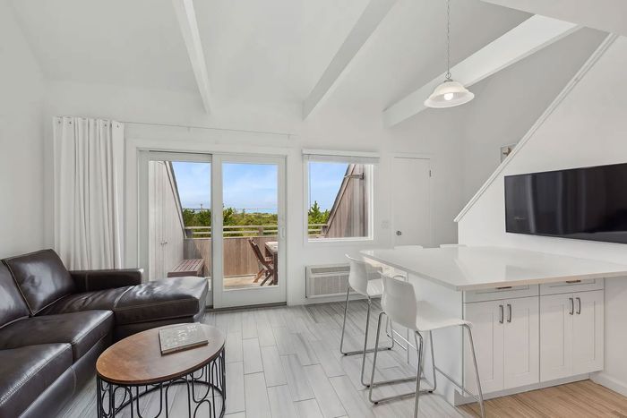 An all-white island and a black leather couch in a listings photo