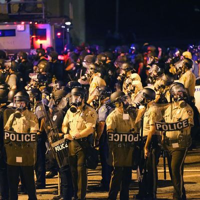 FERGUSON, MO - AUGUST 17: An large group of police officers advance toward demonstrators protesting the killing of teenager Michael Brown on August 17, 2014 in Ferguson, Missouri. Police shot smoke and tear gas into the crowd of several hundred as they advanced near the police command center which has been set up in a shopping mall parking lot. Brown was shot and killed by a Ferguson police officer on August 9. Despite the Brown family's continued call for peaceful demonstrations, violent protests have erupted nearly every night in Ferguson since his death. (Photo by Scott Olson/Getty Images)