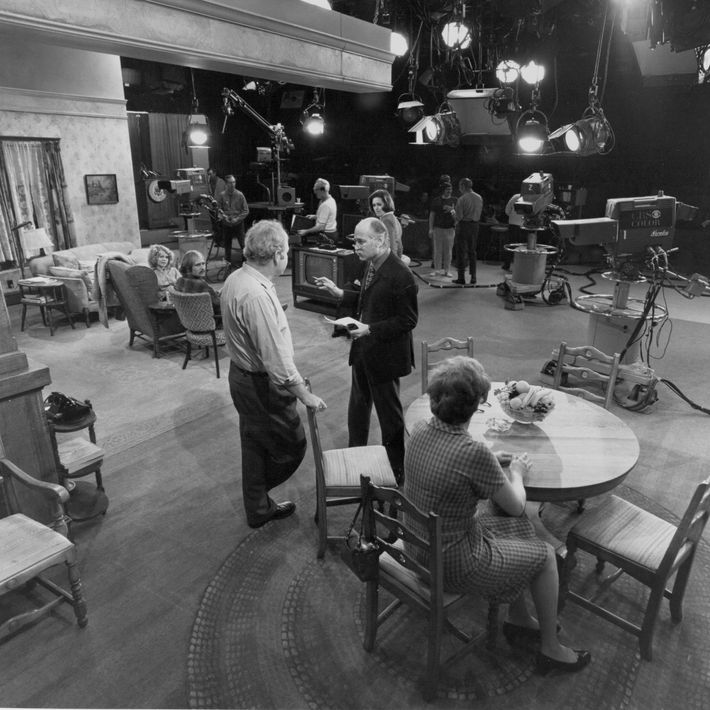 En el set de Todo en familia, 1971. Lear habla con Carroll O'Connor;  Jean Stapleton está sentado a la mesa de la cocina, con Sally Struthers y Rob Reiner en el extremo izquierdo.