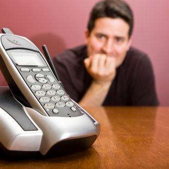 A man nervously waits for the phone to ring.