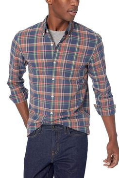A male model wearing a slim-fit long-sleeved white, blue, green, and orange plaid collared button down from Goodthreads over a grey crew neck t-shirt and a pair of dark wash jeans. The Strategist - A Bunch of Men’s Button Downs (From $16) Are on Sale at Amazon.