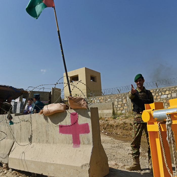 An Afghan National Army soldier gestures outside the gates of a British-run military academy, where an Afghan soldier opened fire on NATO troops inside the premises, on the outskirts of Kabul on August 5, 2014. An Afghan soldier opened fire on NATO troops at a British-run military academy in Kabul on August 5, officials said, adding that casualty details were unconfirmed and the cause of the shooting was unclear. 