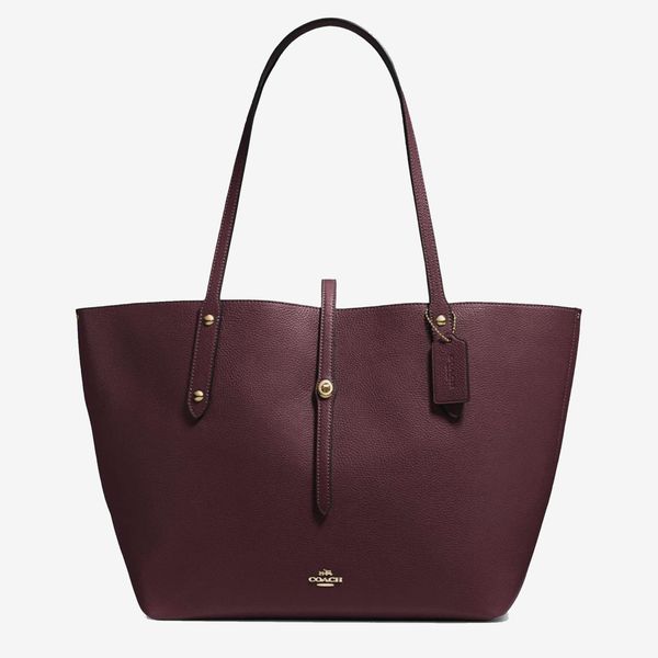 The Coach Market Tote bag in dark red with gold accents, a strap close, and a small gold Coach logo. The Strategist - 48 Things on Sale You’ll Actually Want to Buy: From Sunday Riley to Patagonia