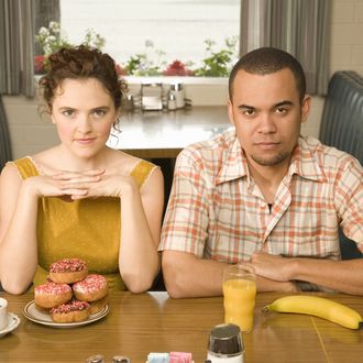 Couple sitting in diner with doughnuts and fruit, portrait
