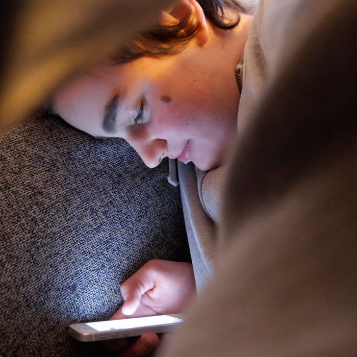 14 year old hanging upside down with iPhone on couch 
