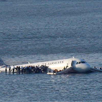 Passengers stand on the wings of a U.S. Airways plane as a ferry pulls up to it after it landed in the Hudson River in New York, January 15, 2009. Local media said the plane was an Airbus with 146 passengers and five crew which had just taken off from La Guardia Airport and was trying to return after apparently striking a flock of birds.