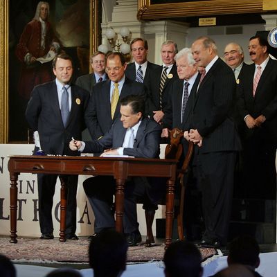 BOSTON - APRIL 12: Massachusetts Governor Mitt Romney signs into law a new health care reform bill during a ceremony at Faneuil Hall April 12, 2006 in Boston, Massachusetts. U.S. Sen. Edward Kennedy (D-MA) (2nd R) and others joined Romney for the signing of the bill, which makes Massachusetts the first state in the country to require that all residents have health insurance. (Photo by Joe Raedle/Getty Images)