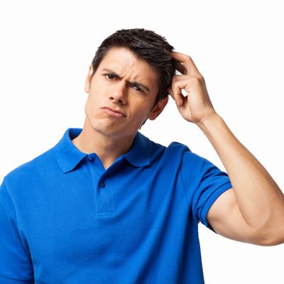 Portrait of confused young man in a casual blue t-shirt scratching his head. Horizontal shot. Isolated on white.