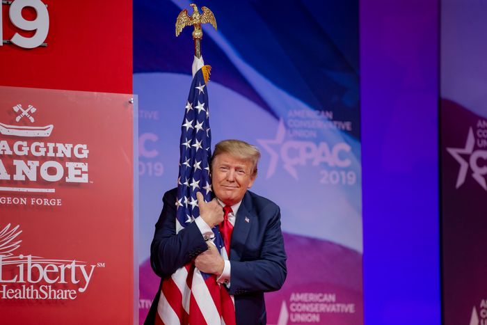 President Donald Trump hugs a flag at CPAC 2019.