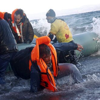 A refugee tries to stand up after falling into the sea as Syrian and Iraqi refugees arrive on a raft on a beach on the Greek island of Lesbos