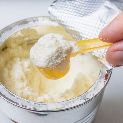 Hand holds scoop with newborn milk formula.