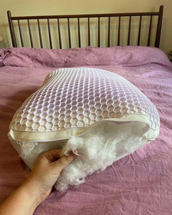 A pillow with a purple grid on top of it, unzipped to show the fiber filling.