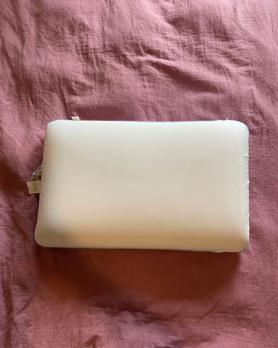 A white pillow on a pink duvet.