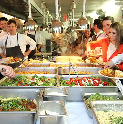 家庭聚餐在山口占据了大约10英尺的空间。厨师们从热的一面靠近，前面的工作人员排成一排，延伸到热的队伍的整个长度，还有几十人在厨房外的走廊上等待。每户人家的一顿饭可以养活一百多人。