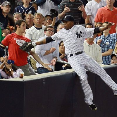 Dewayne Wise #45 of the New York Yankees falls into the stands after making a catch off the bat of Jack Hannahan #9 of the Cleveland Indians in the seventh-inning at Yankee Stadium on June 26, 2012.