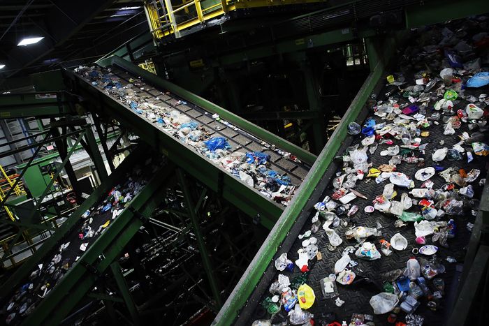 Plastic bottles, cans, glass bottles on two criss-crossing conveyer belts.