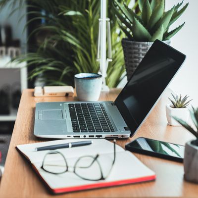 Close Up View Of A Wooden Desk With Laptop, Planner, Mobile Phone, Eyeglasses Left On The Work Table