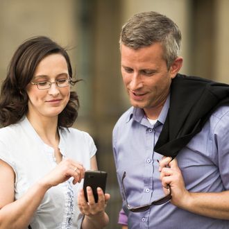 A woman showing a message on a smartphone to a friend.